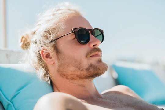 Man wearing sunglasses relaxing on poolside lounge