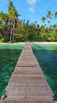 A first person walk along a wooden pier on a tropical beach in sunny day