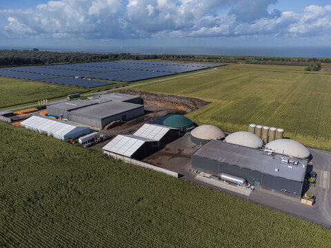Aerial view of a sprawling biogas plant with its rounded domes and solar panels, contrasting against the vast green fields, Groen Gas Almere, Flevoland, Netherlands.
