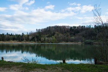 Fototapeta premium Wide lake landscape with forest reflection and blue sky