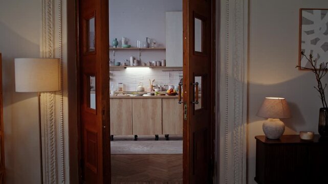 Woman vacuums kitchen dancing during cleanup view through doorway