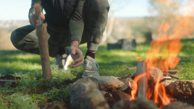 Young Man Preparing Firewood with Axe, Showcasing Campfire Skills