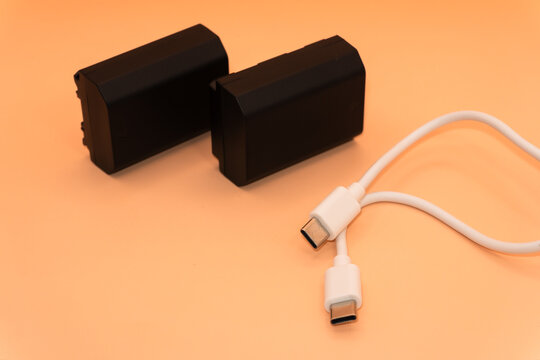 USA type C with two black batteries, USB type A, micro usb, chargers, type c, white usb on a light orange background. High quality