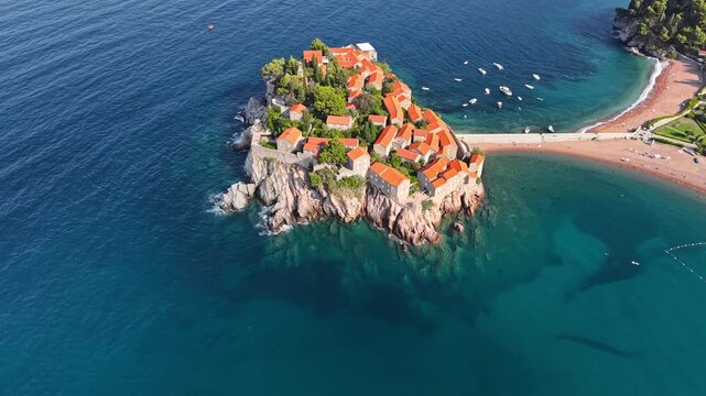 Aerial view of Sveti Stefan, a captivating island village with terracotta roofs, connected by a narrow isthmus to the mainland, Budva Municipality, Montenegro.