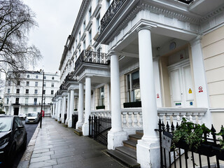 Naklejka premium Elegant white terraced townhouses with classical columns and balconies on a rainy London, UK street