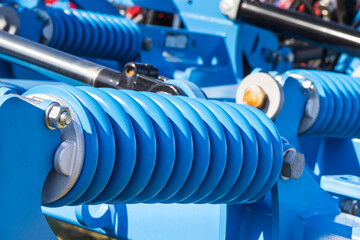 Steel blue spring as part of heavy agricultural, industrial machine. Technology