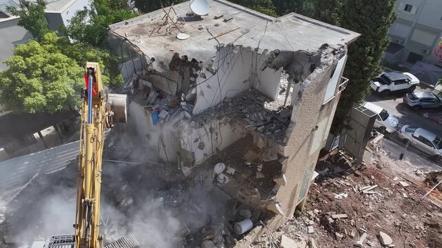 High-Angle Aerial View of a Heavy Duty Excavator Demolishing a Concrete Building at an Urban Construction Site