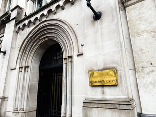 Naklejka premium Historic Parliament Street building entrance with stone arch and brass plaque in London, UK
