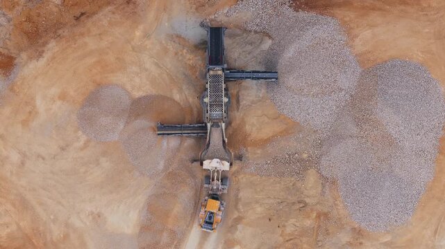 Aerial view of quarry machinery contrasting against the rough textures of the gravel and sand, creating a geometric landscape, Arsoli, Lazio, Italy.