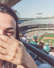 Young woman covering face with hand at baseball stadium