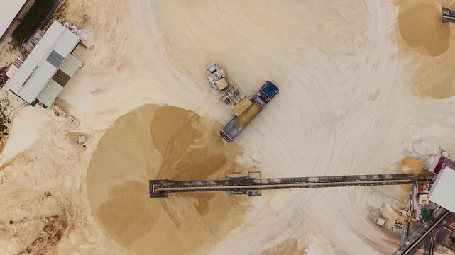 Aerial view of a quarry, the earth tones contrasting with the machinery and conveyor belt system in Arsoli, Lazio, Italy.