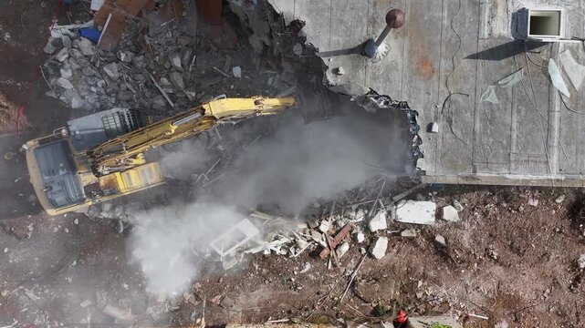High-Angle Aerial View of a Heavy Duty Excavator Demolishing a Concrete Building at an Urban Construction Site