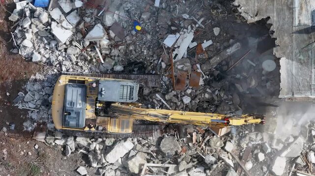 High-Angle Aerial View of a Heavy Duty Excavator Demolishing a Concrete Building at an Urban Construction Site