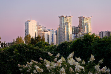 Fototapeta premium Modern city skyline with high-rise buildings and lush greenery at sunset
