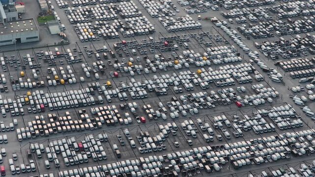 Aerial view of a massive lot filled with rows of tightly packed vehicles, creating an intricate pattern of whites, blacks, and grays, Atessa, Abruzzo, Italy.
