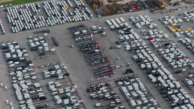 Aerial view of numerous vehicles, mainly white vans, neatly aligned in rows, creating a geometric pattern with contrasting tones, Atessa, Abruzzo, Italy.