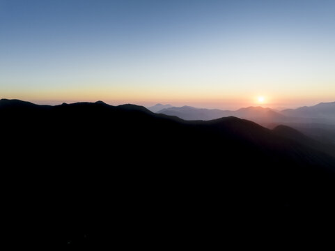 Aerial view of the silhouette of Mount Terminio during a golden sunrise over the Picentini mountain range in Sala, Campania, Italy.