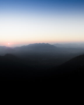 Aerial view of Terminio mountain range with silhouettes of peaks under a soft sunset sky and hazy valley in Sala, Campania, Italy.