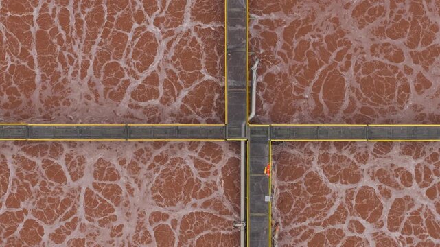 Aerial view of the water treatment plant with its peculiar reddish water and white foam, divided by the grey walkways, Avezzano, Abruzzo, Italy.