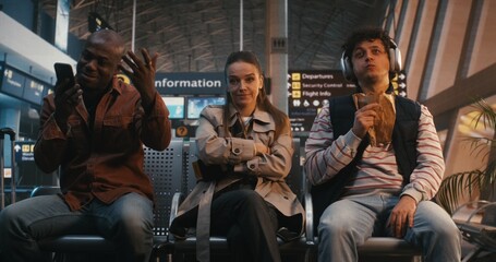 Fototapeta premium Young Stylish Woman Sits in Busy Airport Lounge, Visibly Uncomfortable Among Noisy Strangers. Concept of Social Anxiety, Struggle of Introvert in Public Spaces, and Need For Solitude in Crowd.