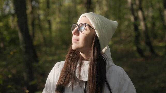 Woman in a warm white jacket appreciating the beauty of autumn woods