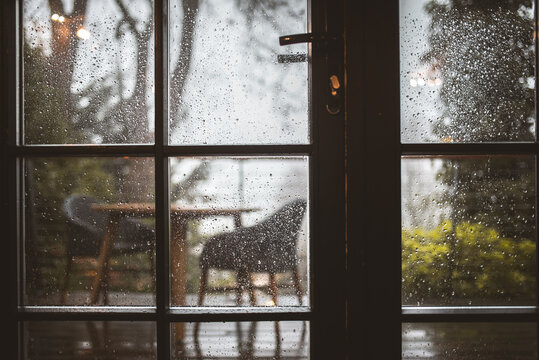 Cozy cafe interior seen through a rain-streaked window on a gloomy day