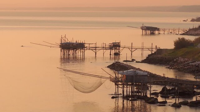 Aerial view of the ancient Trabucchi fishing platforms resting on stilts as dawn casts a golden glow, San Vito Chietino, Abruzzo, Italy.