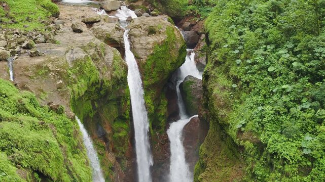 Aerial top view of multi level waterfall flowing over moss covered rocks in dense tropical rainforest of Costa Rica.