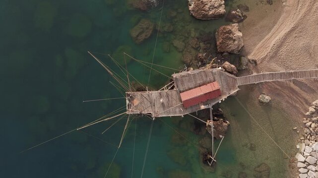 Aerial view of the ancient Trabucco structure contrasting against the turquoise water and sandy beach, San Vito Chietino, Abruzzo, Italy.