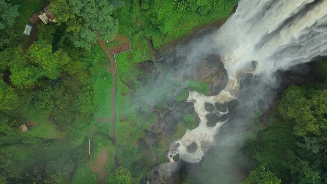 Aerial view of the powerful Curugsewu Waterfall cascading down the rocks, surrounded by lush green forest, Curugsewu, Central Java, Indonesia.