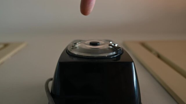 Vintage style timelapse or close-up video of a hand dialing a number on an old black rotary wall telephone, shot from a low angle. Evokes nostalgia, analog communication and classic design with retro 