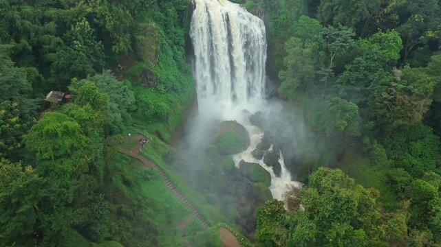 Aerial view of the majestic Curugsewu Waterfall with its powerful cascade surrounded by lush green vegetation, Curugsewu, Central Java, Indonesia.