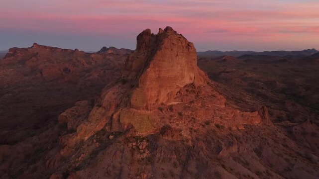 Aerial view of rugged desert terrain and striking mountain rock formations under a soft pink and orange sky, Quartzite, Arizona, United States.