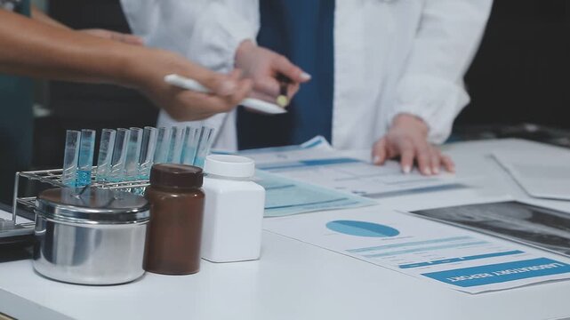 Medical team having a meeting with doctors in white lab coats and surgical scrubs seated at a table discussing a patients working online using computers