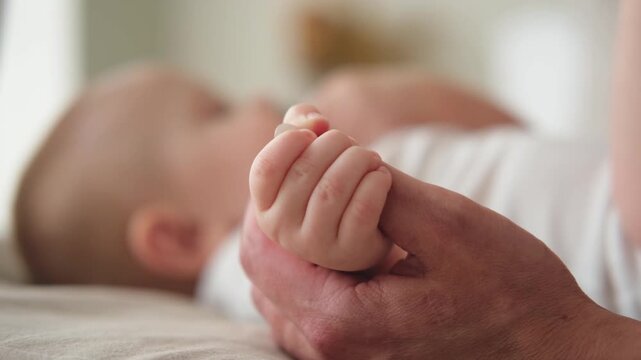 Happy family. Tiny newborn infant baby little hand on mother hand palm. Newborn baby holding parent finger after birth. Mom baby at home. Support protection of new life. Handle with care