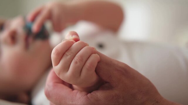 Happy family. Tiny newborn infant baby little hand on mother hand palm. Newborn baby holding parent finger after birth. Mom baby at home. Support protection of new life. Handle with care