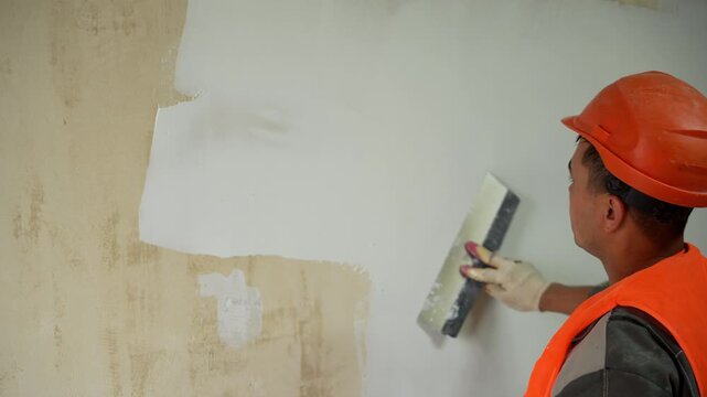Close up of worker applying plaster with trowel on wall