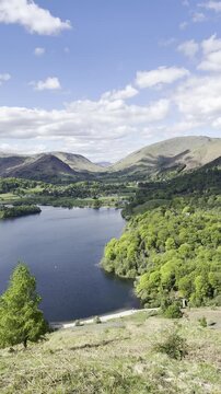 High viewpoint video of Grasmere Lake and Rydal Water showing expansive landscape with calm water, trees and hills under scattered clouds, England, UK.