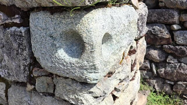 Sayacmarca, Peru - 26 June 2024. Close view of an Inca stone doorway element with a circular hole carved into a granite block, fitted into a dry stone wall along the Inca Trail.