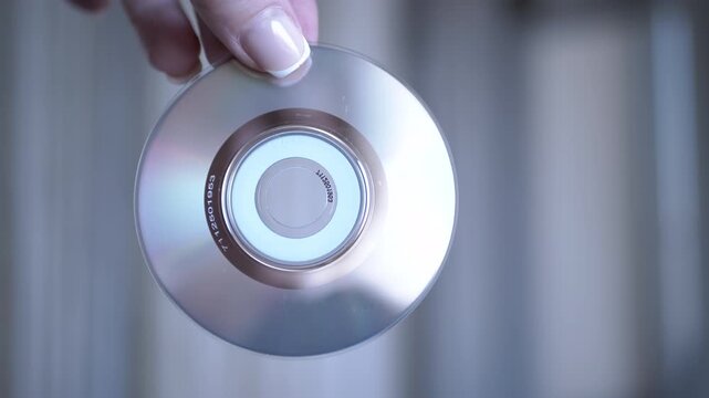 A hand presents a CD-R against a blurred background, ready for data or music recording. Ideal for technology or nostalgia themes.