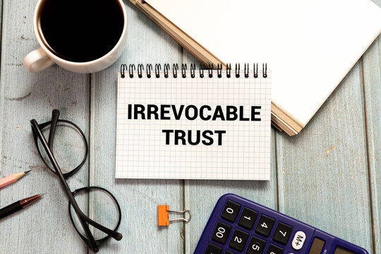 IRREVOCABLE TRUST text on sticker with pen on the black background.