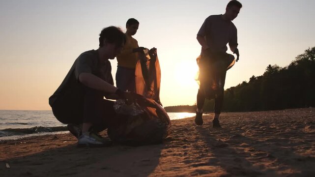 Earth day. Volunteers activists collects garbage cleaning of beach coastal zone. Woman and mans puts plastic trash in garbage bag on ocean shore. Environmental conservation coastal zone cleaning