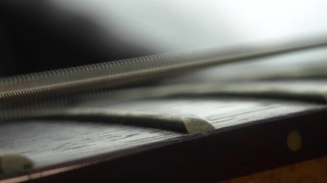 Close-up of an electric guitar neck showing a string vibrating after being plucked, creating a visible wave motion. Detailed macro shot highlighting sound, resonance, and musical dynamics.
