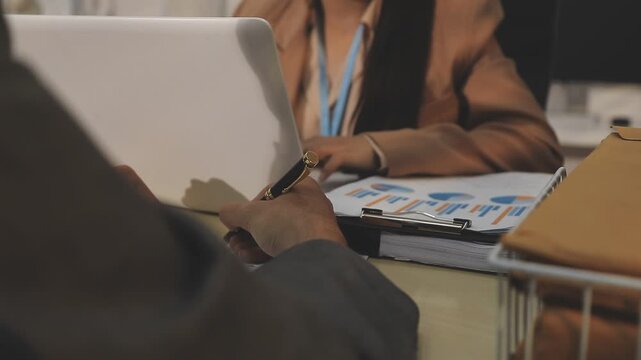 Close up of businessman or accountant hand holding pen working on calculator to calculate business data, accountancy document and laptop computer at office, business concept