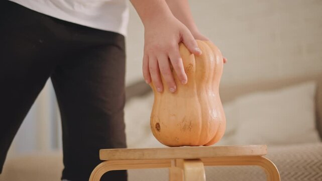Person baker setting pumpkin on small stool still life display with bedroom background gentle hand placement then step back wooden table neutral palette soft morning light ready for carving or baking