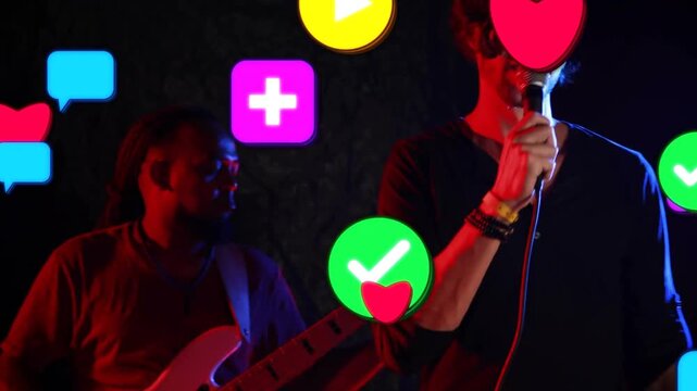 Singer singing and moving on dim music stage, causing social icons floating over band, showing buzz