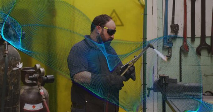 Male fabricator inspecting torch controls and heating metal, blue overlay partly obscuring subject