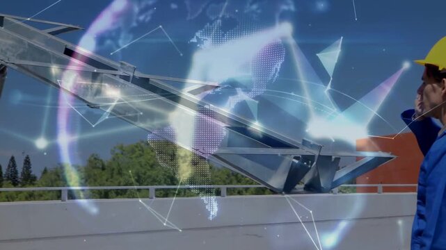 Worker receiving call, leaning and aligning solar frame while digital globe intensifying on roof