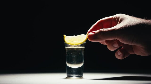 Mexican Tequila Mezcal pouring with lime and salt on a stone table. Strong vodka rum alcoholic drink is poured from a bottle into a shots.