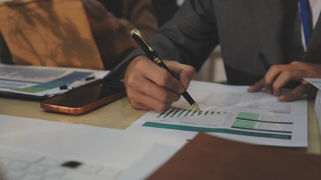 Close up of businessman or accountant hand holding pen working on calculator to calculate business data, accountancy document and laptop computer at office, business concept